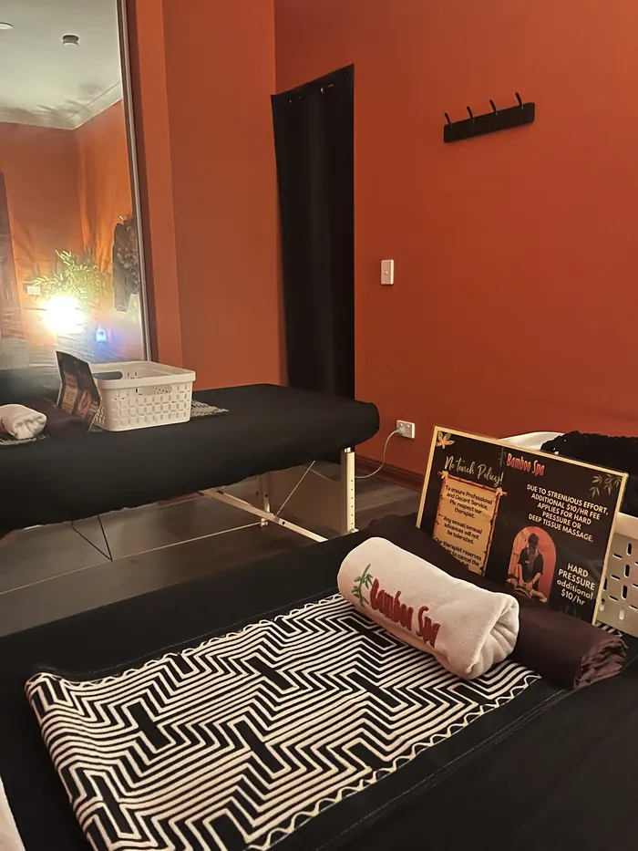A treatment bed dressed with a black-and-white runner and an embroidered Bamboo Spa towel