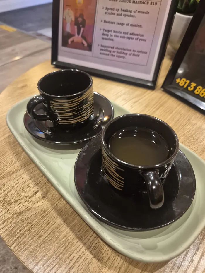 Two black-and-gold tea cups on a tray at reception